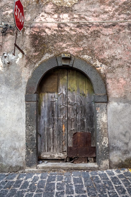 Old wooden entrance door on facade of antique baroque building in traditional architecture of Catania Sicily, Italy.