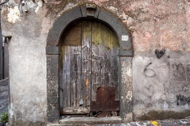 Old wooden entrance door on facade of antique baroque building in traditional architecture of Catania Sicily, Italy.