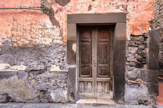 Old wooden entrance door on facade of antique baroque building in traditional architecture of Catania Sicily, Italy.