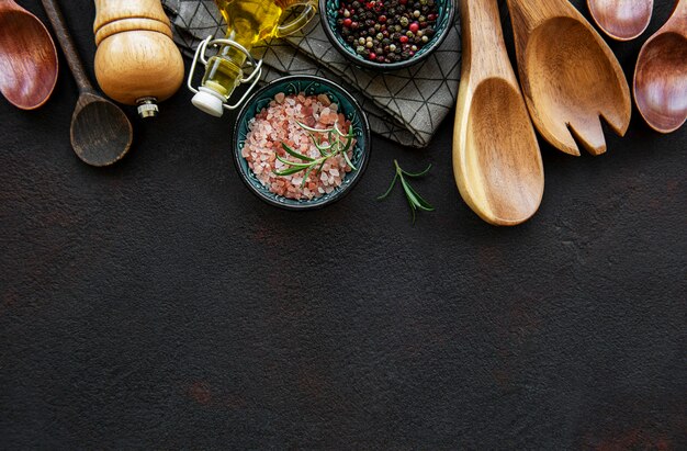 Old wooden kitchen utensils and spices as a border on a black background