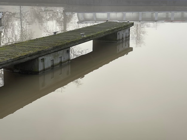 Old wooden pier in the river under grey gloomy sky