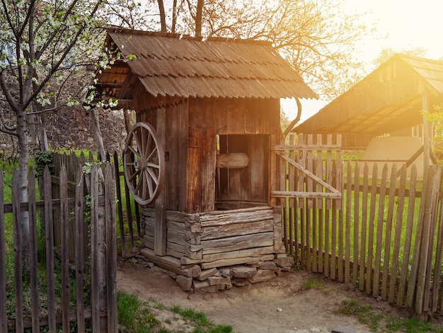 Old wooden rustic well against the background of a flowering garden