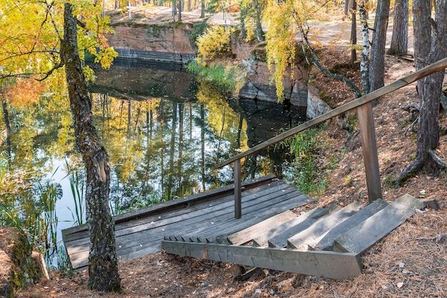 An old wooden staircase and bridge near an abandoned pond Autumn trees are reflected in the water