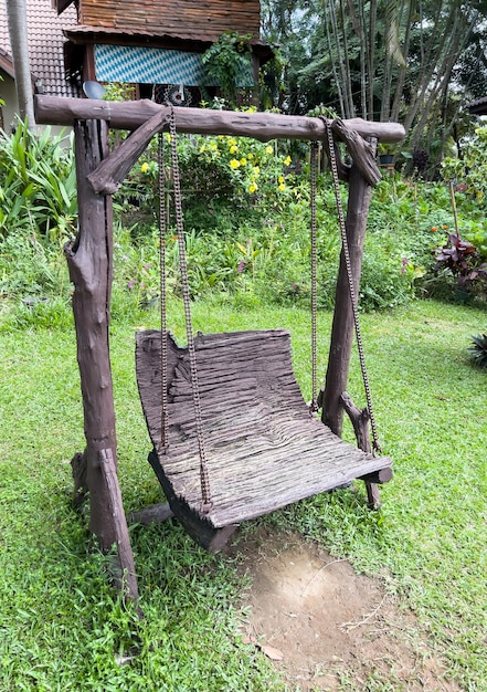 The old wooden swing with the metal chain for playing in the garden of the countryside house, front view with the copy space.