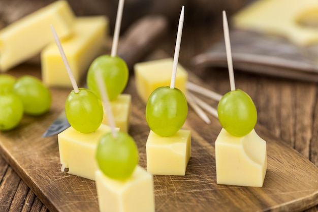 Old wooden table with Cheese blocks and grapes partyfood