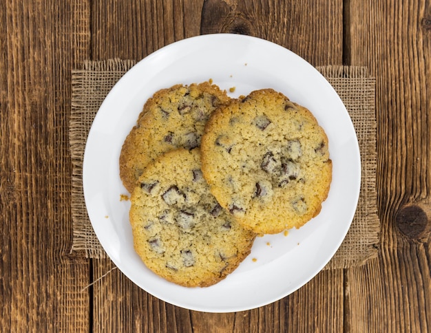 Old wooden table with fresh Chocolate Chip Cookies closeup shot selective focus