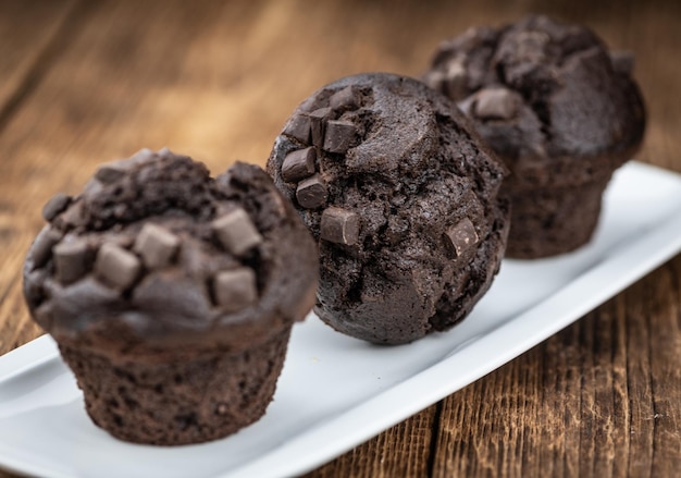 Old wooden table with fresh Chocolate Muffins closeup shot selective focus