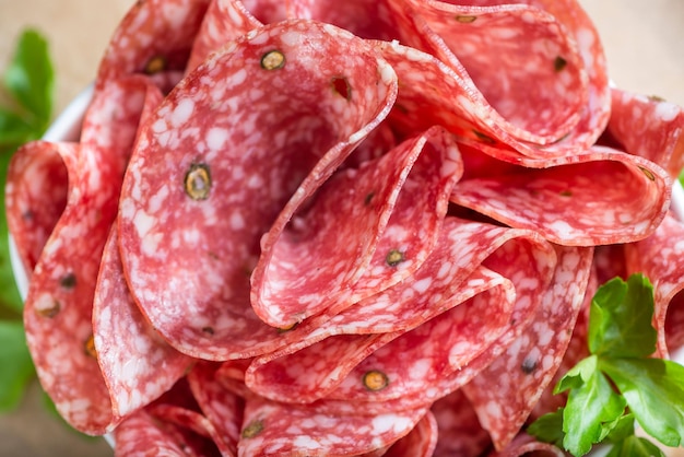 Old wooden table with sliced Salami