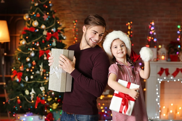 Older brother and little sister in Santa hat with gift  on Christmas background