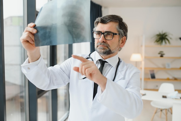 Older man doctor examines xray image of lungs in a clinic