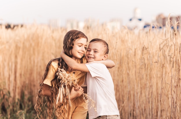 Older sister walks with her brother in nature in the summer. Happy kids sibling walking and playing. Kids play outdoors