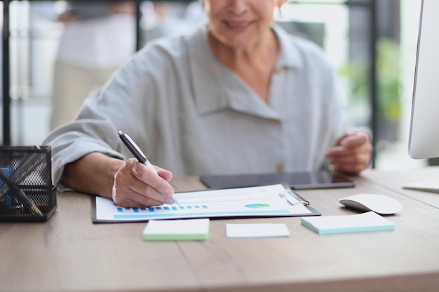 The older stylish woman takes notes in a document