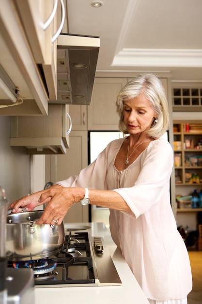 Older woman boiling water on kitchen stove top