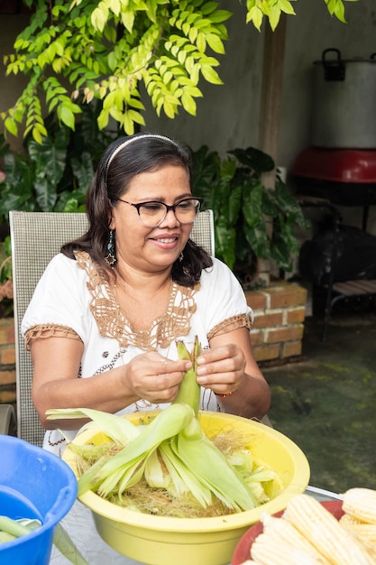 Older Woman cooking in the backyard They are shelling corn Local food concept