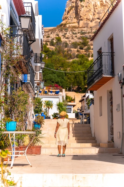 An older woman tourist visiting the Santa Cruz neighborhood in Alicante Mediterranean house Travel for the elderly