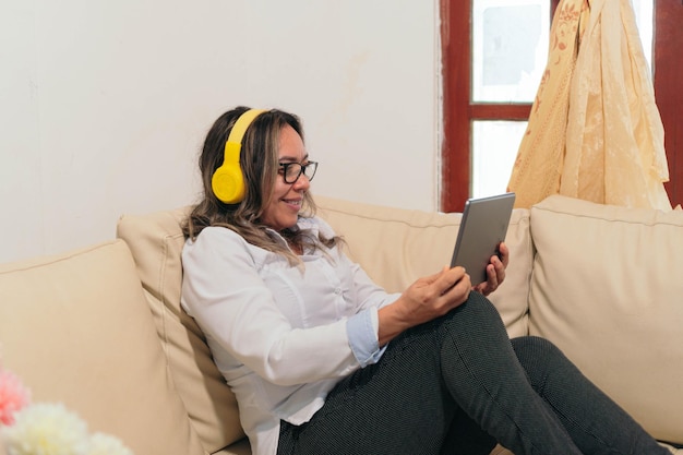 Older woman with headphones watching a movie on a tablet