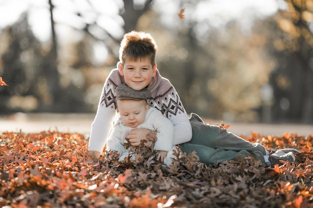 the oldest child hugs and communicates with his 6monthold brother children sitting in the park spend time together