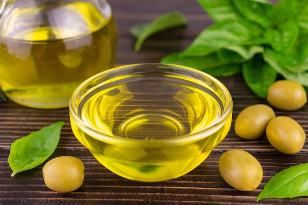 Olive oil in a glass bowl and balelik leaves on a dark background.