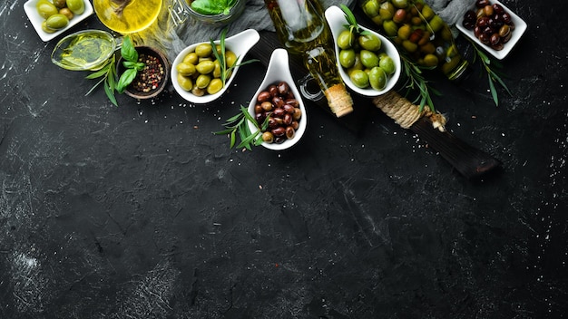 Olive oil olives and spices on a black stone background Top view Free space for your text