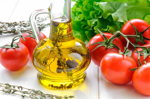 Olive oil and tomatoes on white wooden table