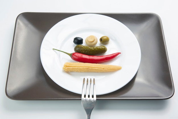 Photo olives, pickled cucumber, pepper, mushrooms and corn in a salad on a plate. food and vegetables. diet and weight loss