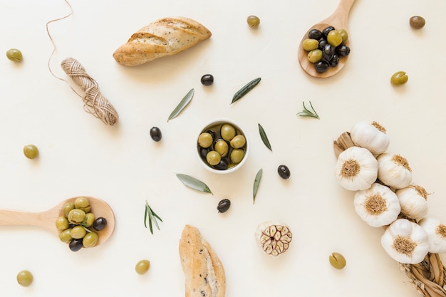 Olives in plate and spoons with garlic and bread