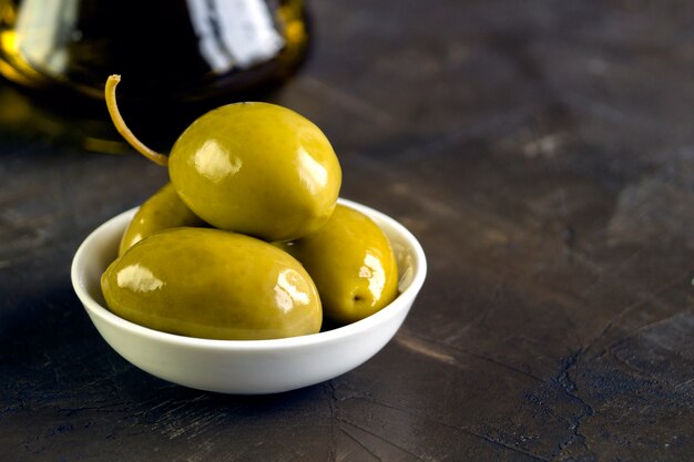 Olives in white bowl on dark background.