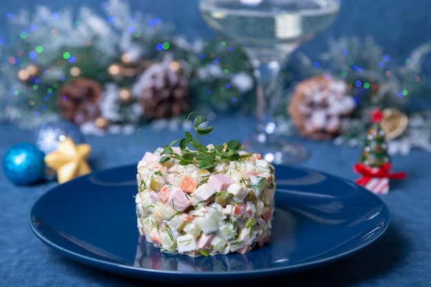 Olivier salad on a blue plate, decorated with pea sprouts. Traditional New Year and Christmas Russian salad