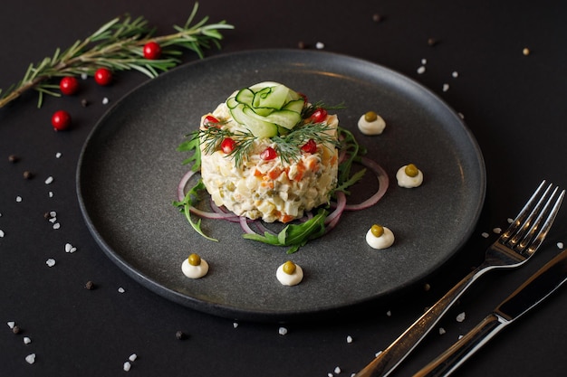 Olivier salad for Christmas on a black table, European holiday food