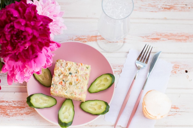 Olivier salad on a plate Bouquet of fragrant peonies serving dishes in the restaurant