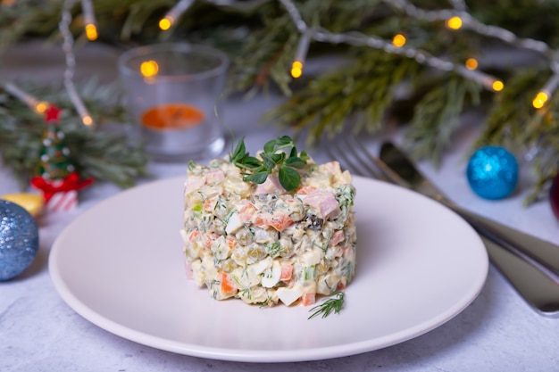 Olivier salad on a white plate decorated with pea sprouts Traditional New Year and Christmas Russian salad Closeup selective focus