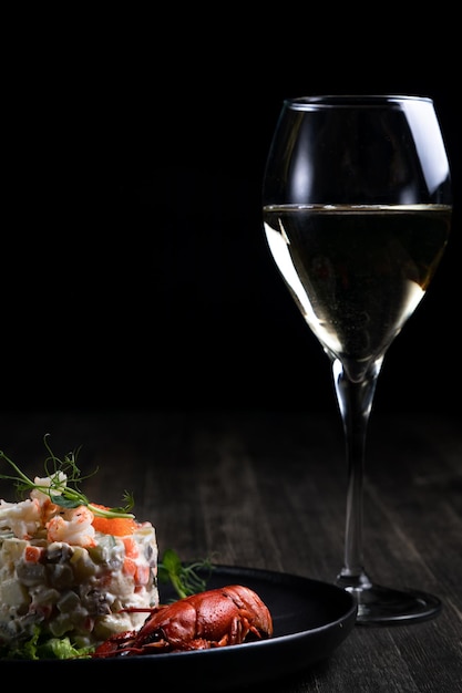 Olivier salad with red caviar served with boiled crayfish and wine