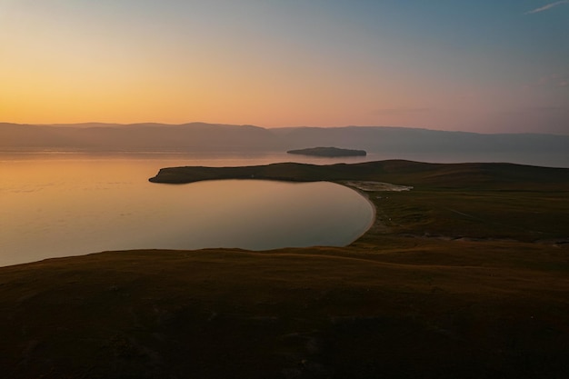 Olkhon Island at sunrise, the largest island in Lake Baikal in eastern Siberia. Shamanka Rock on Baikal lake near Khuzhir at Olkhon island in Siberia, Russia.