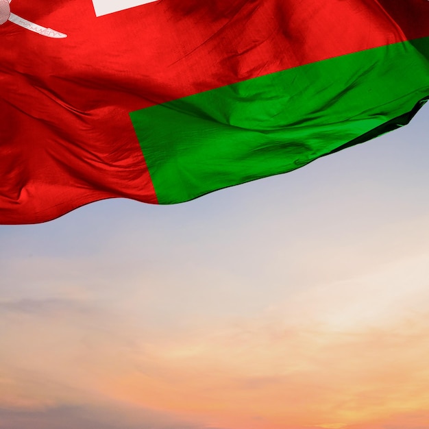 Photo a oman flag with a cross on it flies in the sunset