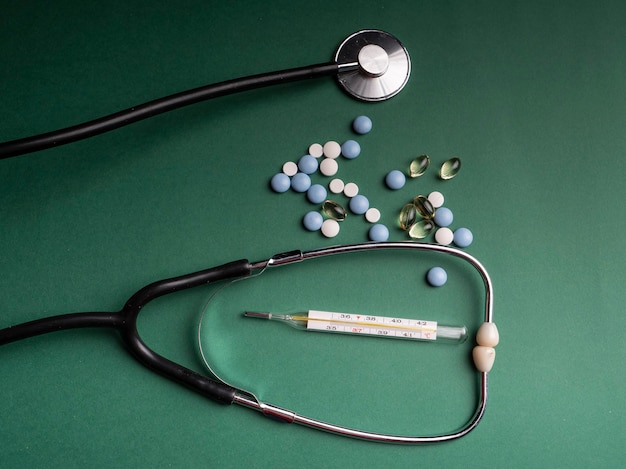 Omega 3 capsules, a stethoscope in which a thermometer lies and various medical pill