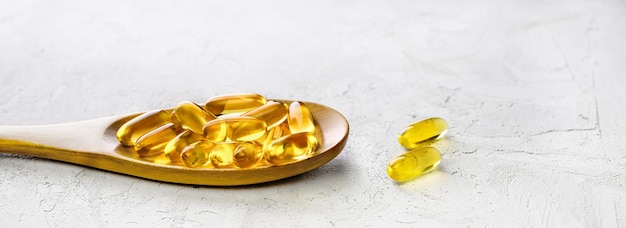 Omega 3 capsules in wooden spoon on shabby concrete background