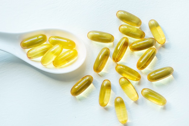 Omega 3 fatty acid capsules in a spoon on a white background close up