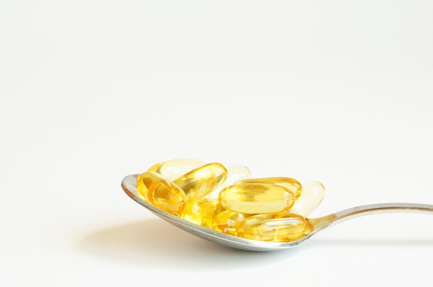 Omega 3 fish oil capsules in silver spoon on white background.  Concept of healthcare.  Copy space.