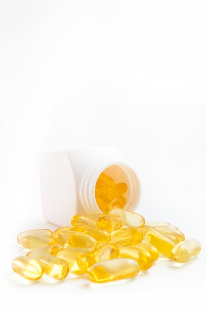 Omega 3 pills pouring out of the jar on a white background