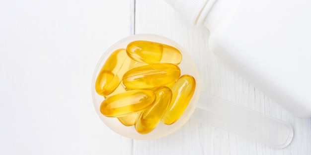 Omega-3 yellow capsules in a plastic scoop, nutritional supplements, close-up, top view.