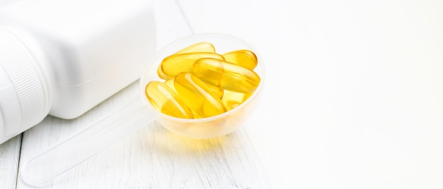 Omega-3 yellow capsules in a plastic scoop, nutritional supplements, close-up view.