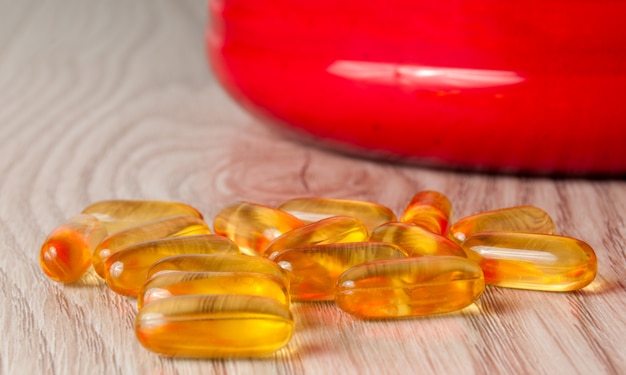 Omega3 fish oil capsules in shape on wooden background