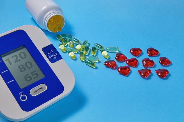 Omega3 polyunsaturated fatty acids and red decorative and cardiac tonometer on a blue background Prevention and treatment of atherosclerosis hypertension and ischemic disease