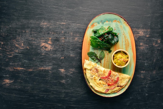 Omelet with spinach and tomatoes Breakfast On a wooden background Free copy space Top view