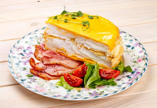 Omelette layered with fried bacon and fresh vegetables Breakfast