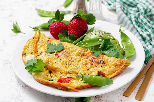 Omelette with tomatoes feta cheese and avocado on white plate