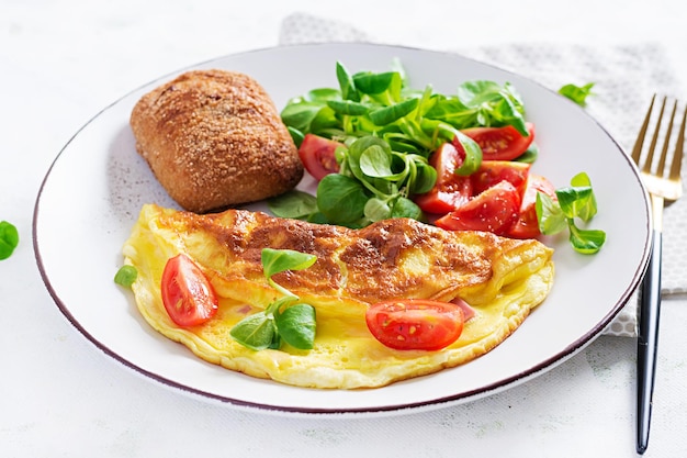 Omelette with tomatoes, ham, cheese and corn salad on plate.  Frittata - italian omelet.