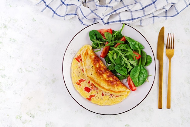 Omelette with tomatoes and salad on white plate Frittata italian omelet Top view