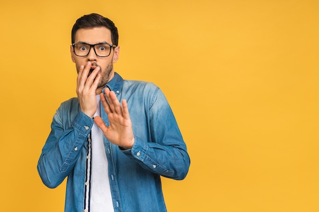 OMG It's incredible Portrait of handsome young man looking at camera while standing isolated over yellow background Close up portrait of bearded man keeping his mouth open