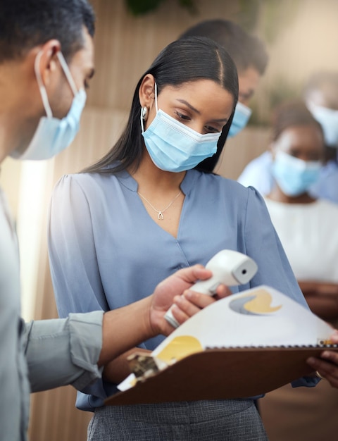 Once the screening is done she can get to work Cropped shot of an attractive young businesswoman wearing a mask and going through covid screen while standing at the head of a queue in her office